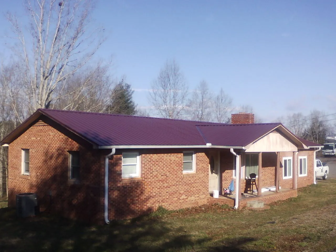 Burgundy metal roof on a brick ranch home with a new addition in Saint Stephen