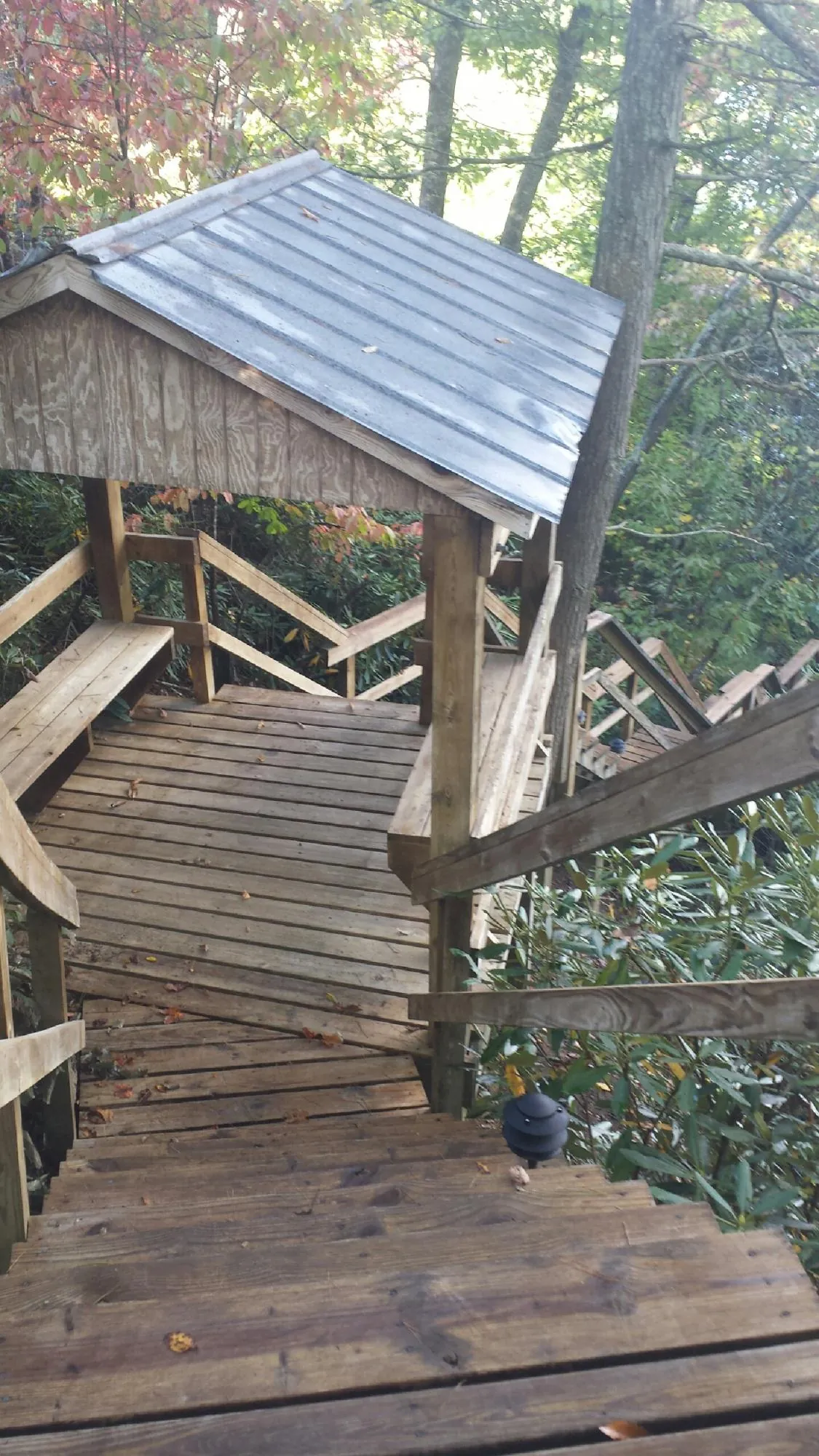 Metal roofed shelter over wooden steps on a wooded walkway — Skylight Repair & Installation work by our crew in Saint Stephen